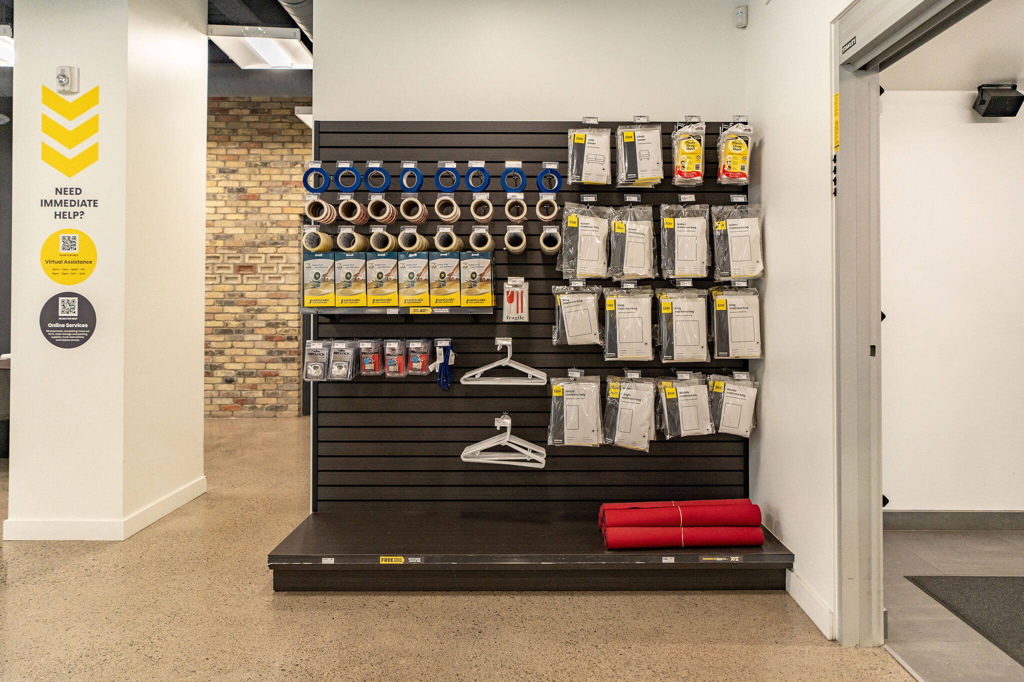 Wall of packing supplies with tape rolls, hangers, and mattress bags at XYZ Storage Toronto Downtown.