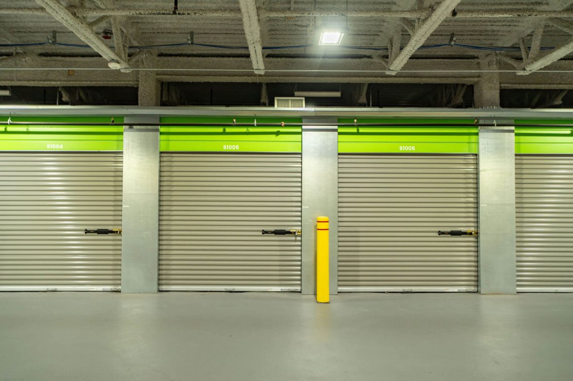 Row of storage units with grey doors and neon green panels displaying white unit numbers at XYZ Storage Toronto Downtown.